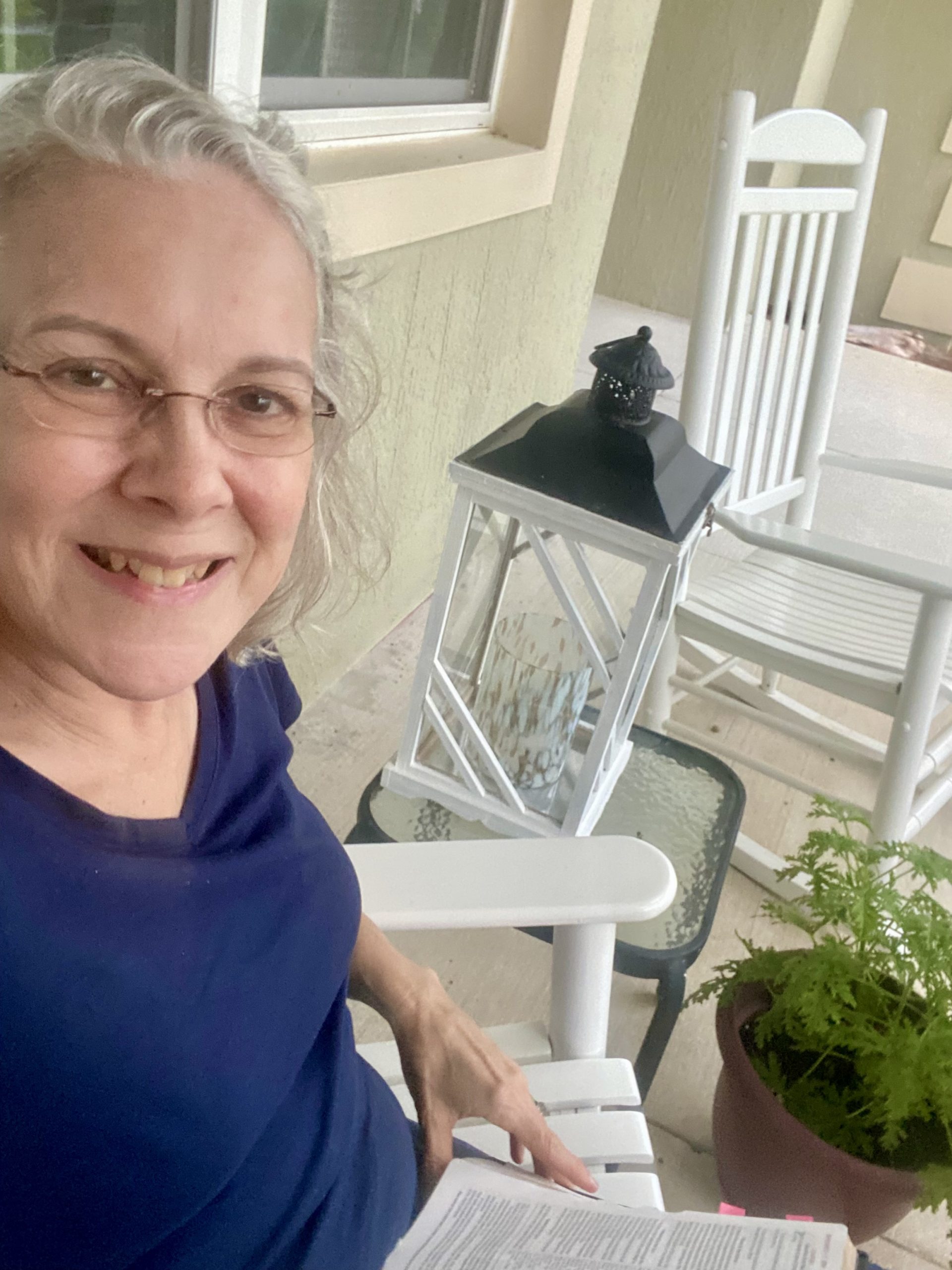 Person reading Bible on a porch chair.